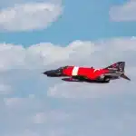Advanced target drone in high-altitude flight, performing aggressive maneuvers against clear sky