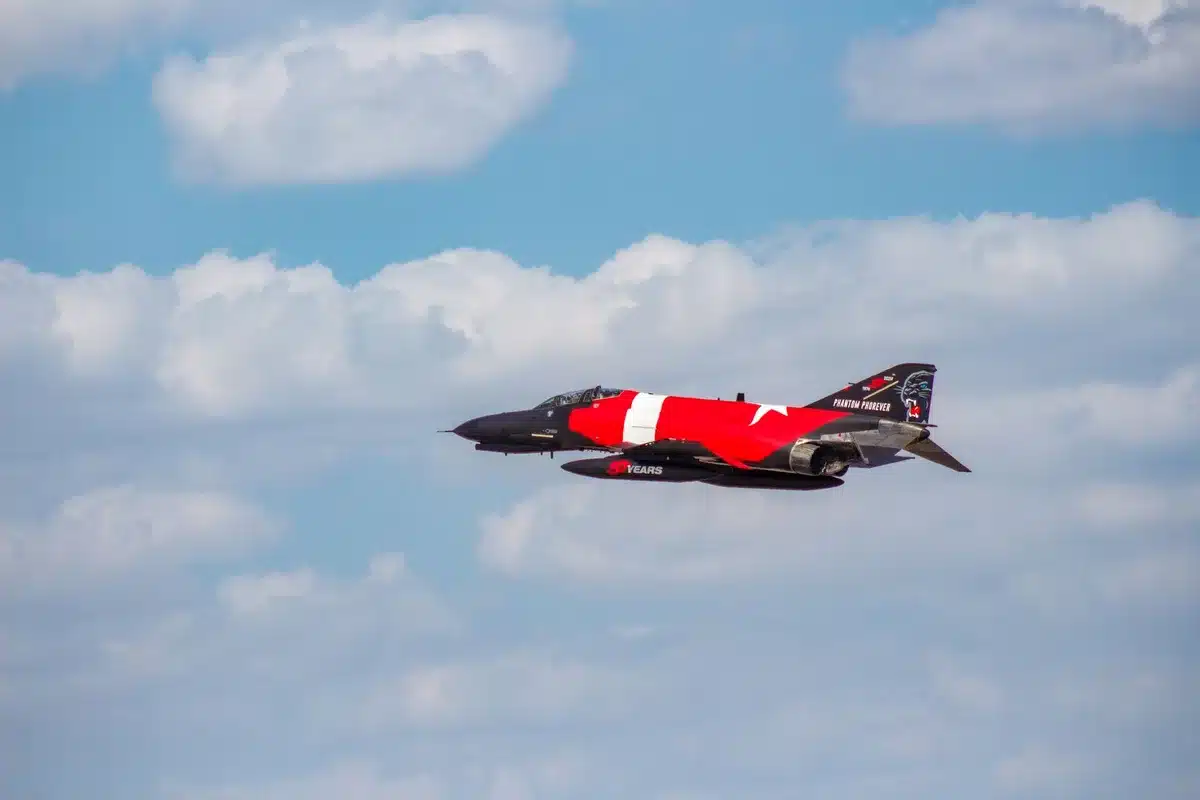 Advanced target drone in high-altitude flight, performing aggressive maneuvers against clear sky