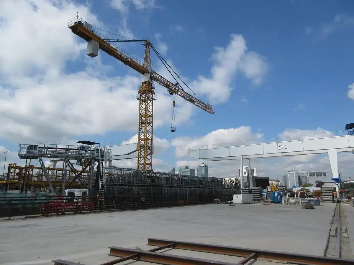 Shipyard scene showing massive hull construction and cranes illustrating the scale of naval building projects and their