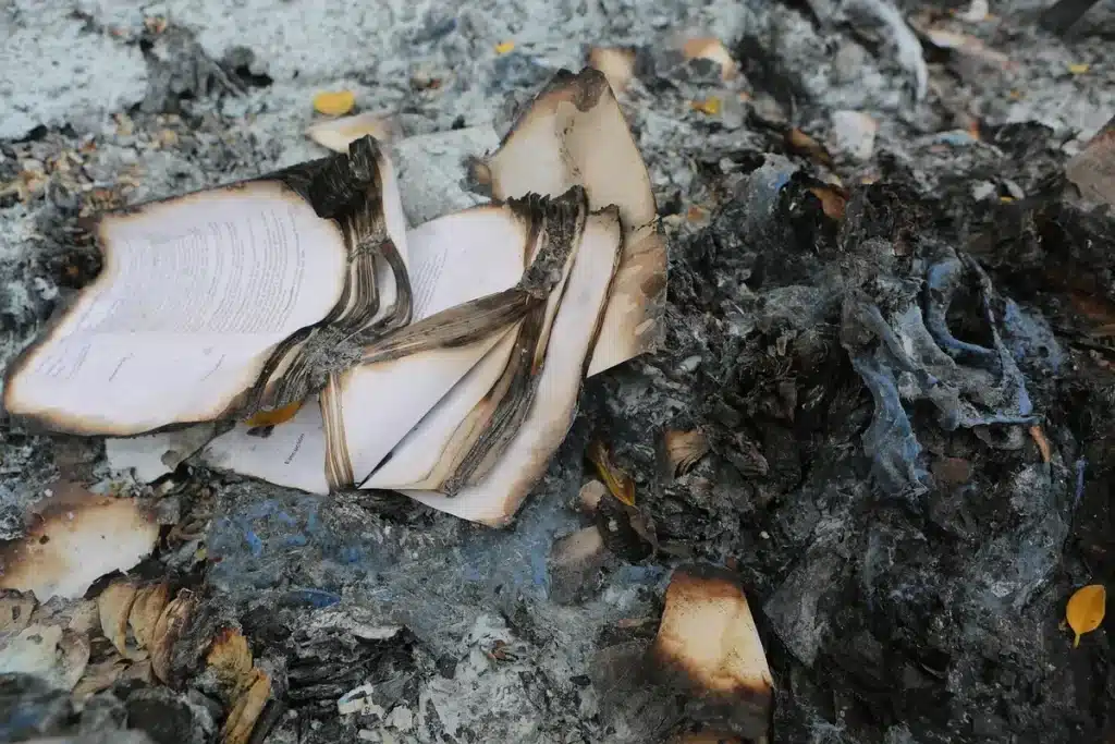 Anonymized burned military aircraft wreckage and scorched hangars at a desert base