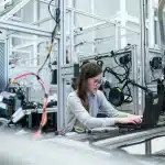 Factory floor with pallets of unbranded aerospace components and a silhouetted worker
